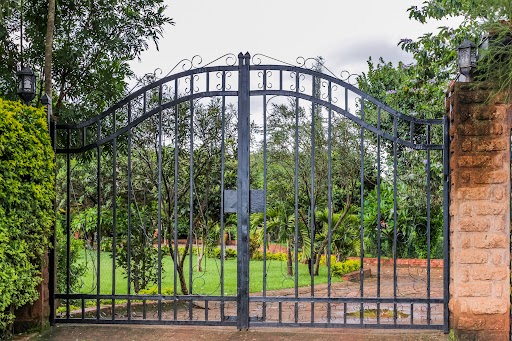 An iron gate with trees and grass surrounding it.