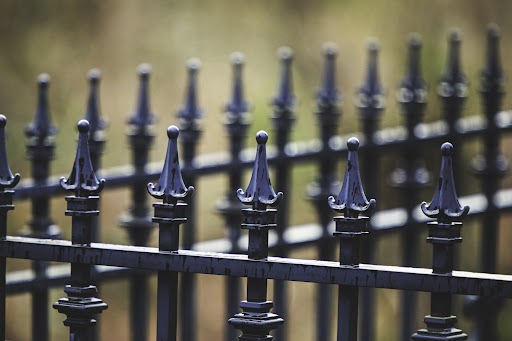 A high angle shot of a metal fence with pointy finials.